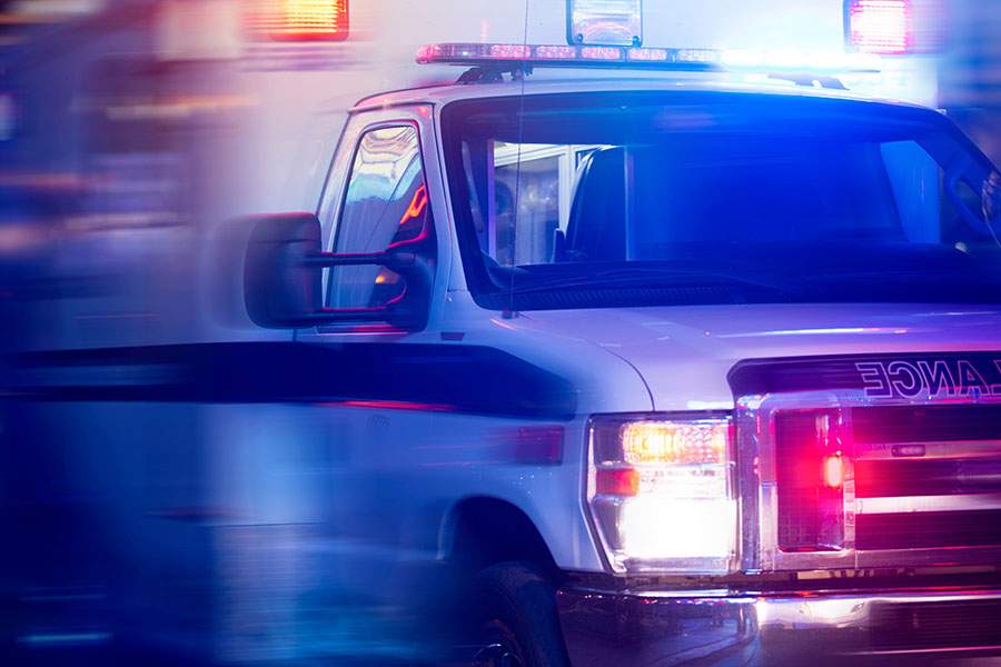 Ambulance with flashing red and blue lights moves quickly, indicating an emergency response in progress.