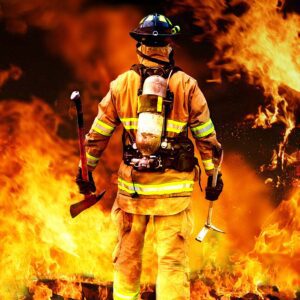 Firefighter with an axe walking near flames.