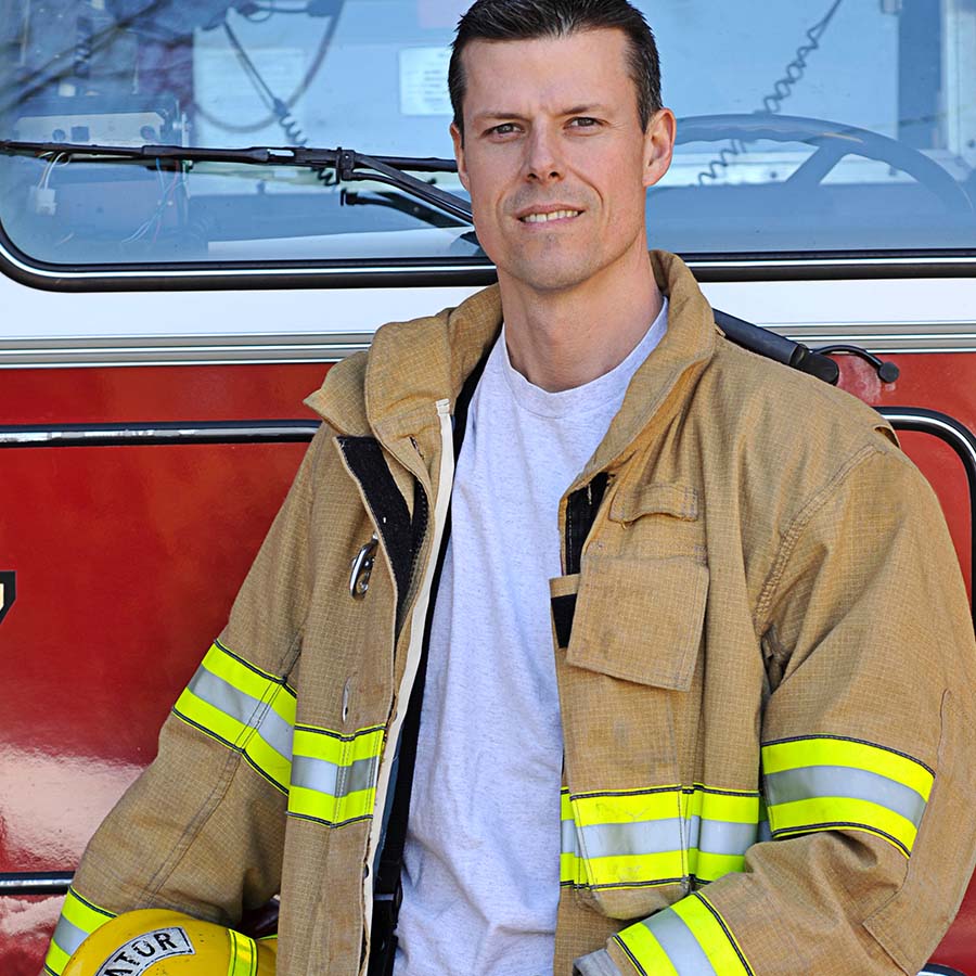 firefighter standing in front of truck with jacket open