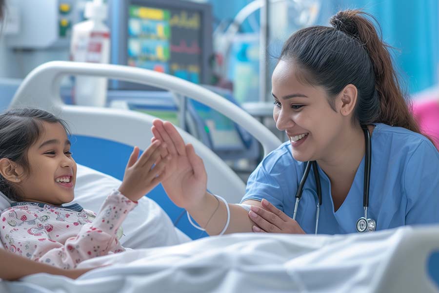 A nurse with a stethoscope high-fives a smiling child in a hospital bed. Medical equipment is visible in the background.