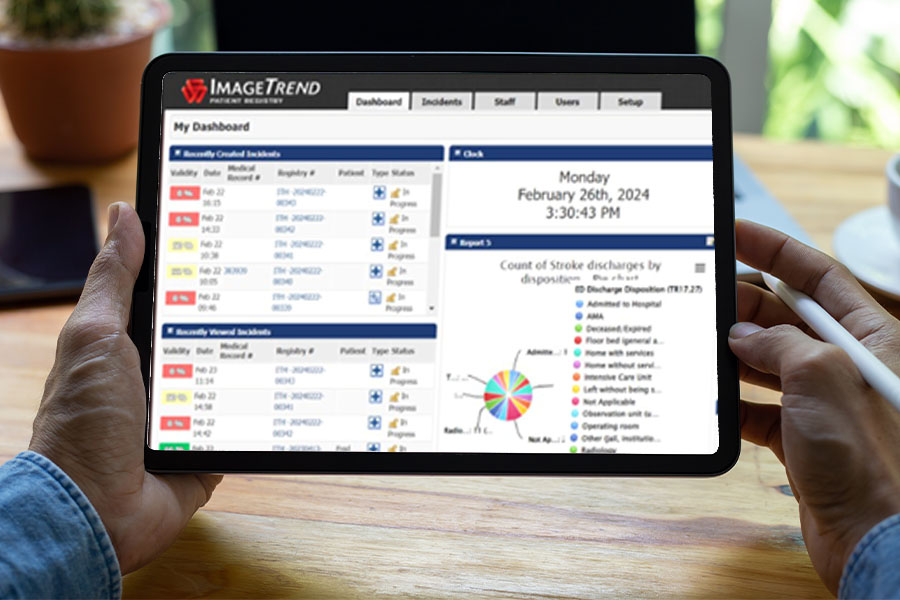 Person holding a tablet displaying a software dashboard with statistics, pie chart, and details related to stroke discharges.