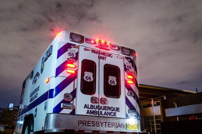 Ambulance with illuminated lights and Route 66 markings at night, Albuquerque, signage for Presbyterian health care.