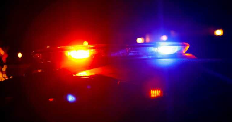 Police car with flashing red and blue lights at night.