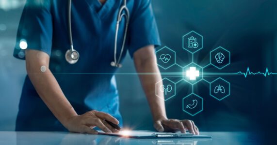 A healthcare professional in blue scrubs interacts with a digital interface displaying medical icons, including a heart and lungs, symbolizing modern medical technology and care.