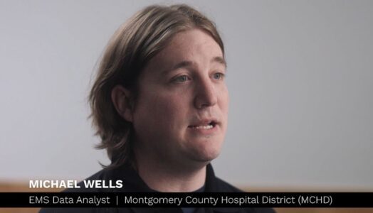 A person with shoulder-length hair speaks in an interview. Text on screen reads: "Michael Wells, EMS Data Analyst, Montgomery County Hospital District (MCHD).