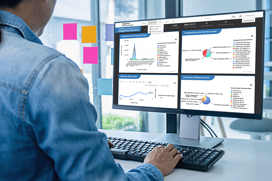 Person working at a desk, viewing graphs and charts related to financial services data on a dual-monitor computer setup.