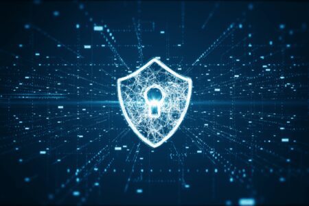 A digital shield with a keyhole symbol is centered on a dark background with glowing network lines and data points, representing cybersecurity or data protection.