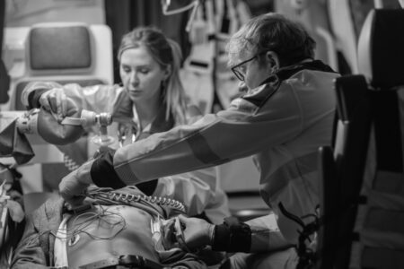 Two emergency medical workers attend to a patient using resuscitation equipment and monitoring devices inside an ambulance.