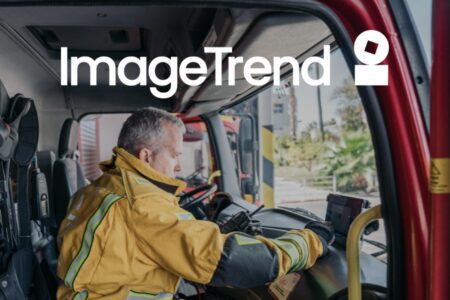 A firefighter in uniform sits inside a fire truck, looking at a device on the dashboard. "ImageTrend" and a logo are overlaid at the top of the image.