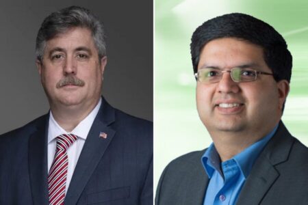 Two men in business attire; the man on the left has gray hair and a mustache, while the man on the right wears glasses and has dark hair. Each stands before a neutral background.
