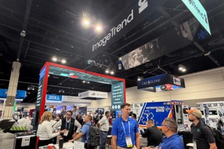 Trade show floor with company booths, including ImageTrend, Zoll, Crestline, and NERIS, with a Metropolitan EMS ambulance on display.