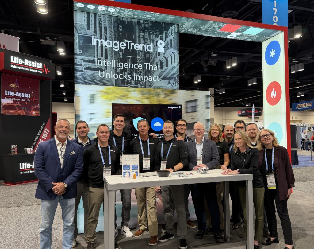 Thirteen people stand in front of an ImageTrend and NERIS trade show booth.