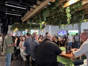 People socialize at a NERIS bar equipped with golf simulators and televisions playing sports.